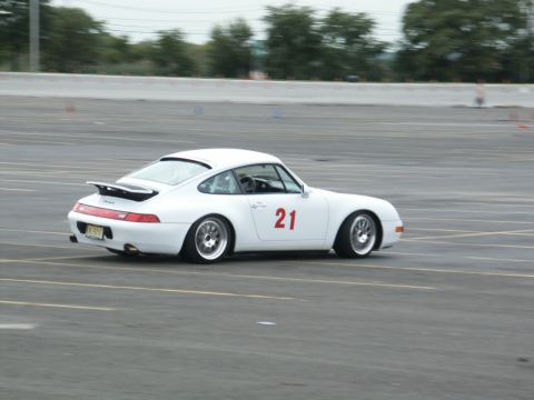 2001 Mercury Grand Marquis - A white Porsche 911 with racing number 21 is captured in motion on a paved track.