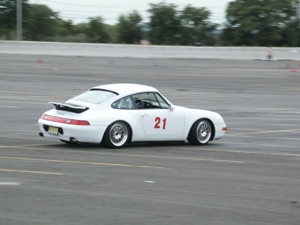 White Porsche 911 with red number 21 on the door, driving on a track