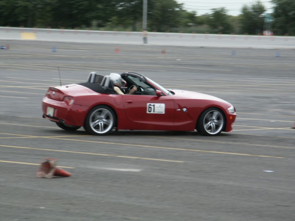 Red convertible sports car with racing number 61 on the door, driving on a paved track