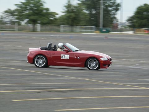 2001 Mercury Grand Marquis - A red convertible with a racing number is seen on a paved track with cones in the background.