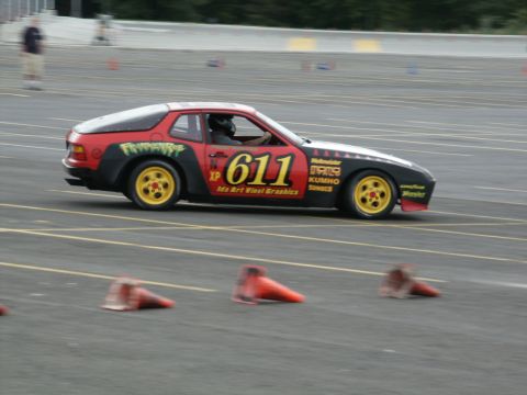 2001 Mercury Grand Marquis - A race car navigates a course marked by traffic cones, displaying sponsor logos and the number 611.