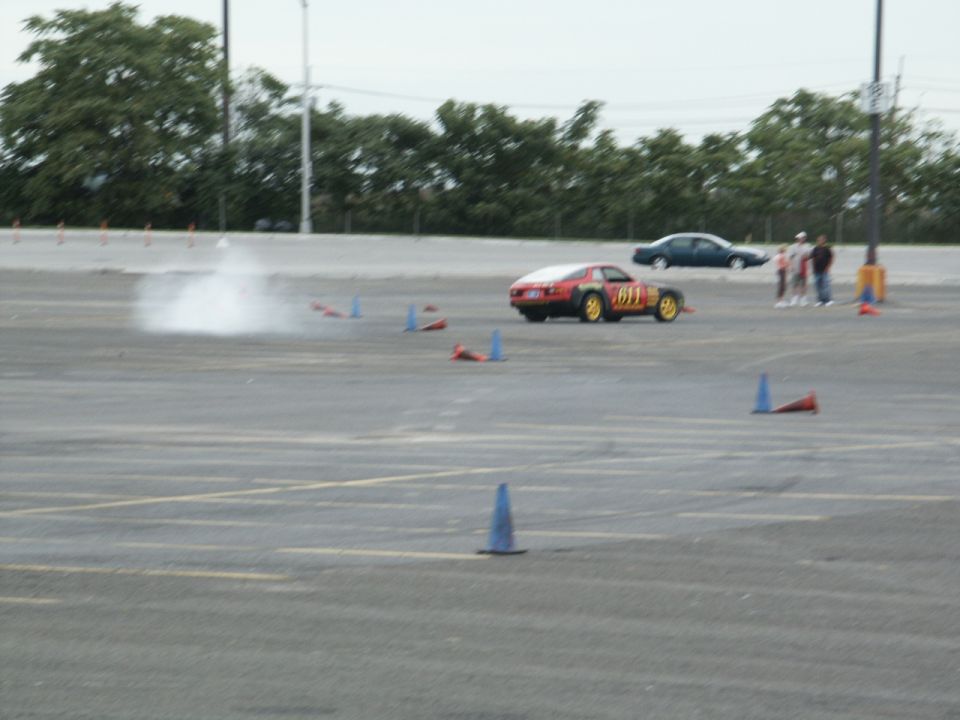 Red and black sports car with yellow wheels doing a donut, emitting smoke