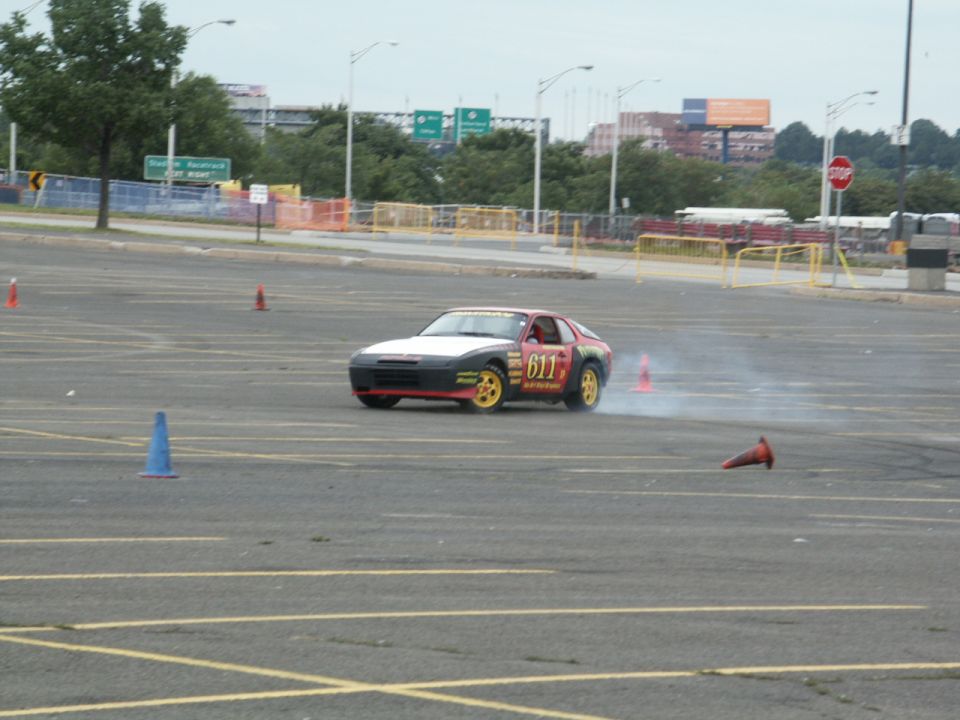 Porsche 944 with number 611 on the door doing a drift in a parking lot