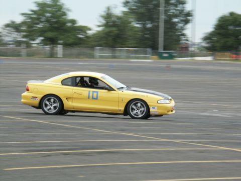 2001 Mercury Grand Marquis - Yellow coupe with black stripe and number 10 on side, seen in a motorsports event.