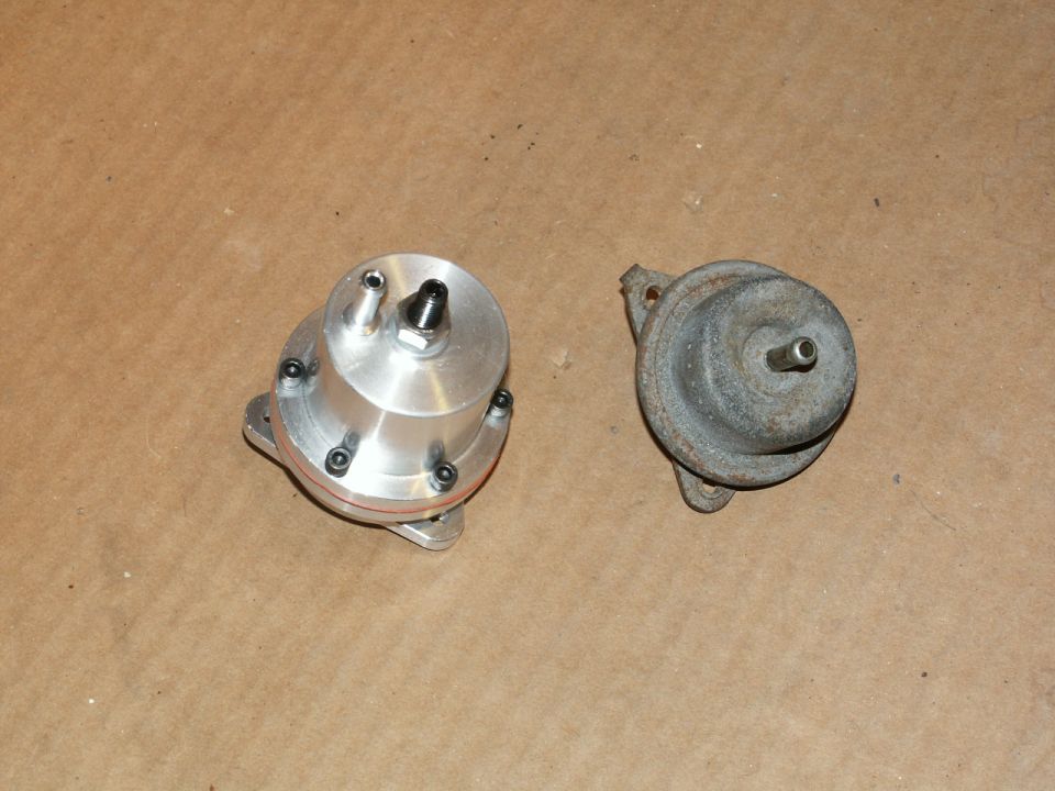 Two fuel pressure regulators, one shiny aluminum and one rusted metal, on a brown surface