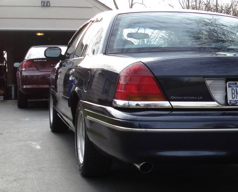 2000 Ford Crown Victoria - A dark 2000 Ford Crown Victoria LX is parked in a driveway, with another vehicle visible behind it.