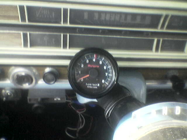1969 Ford F-250 interior with a tachometer mounted on the steering column. The dashboard has horizontal vents and a radio