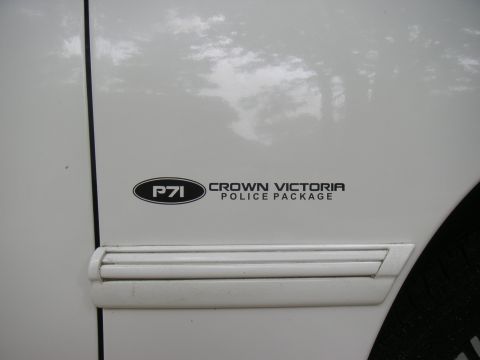 1997 Ford Crown Victoria - A close-up view of a sticker on a white vehicle indicates it is a Crown Victoria Police Package.