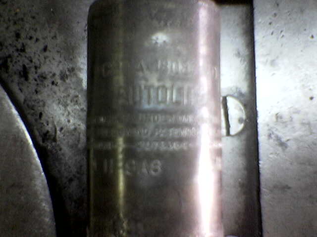 Close-up of a metal cylinder with embossed text, possibly a part from a vehicle