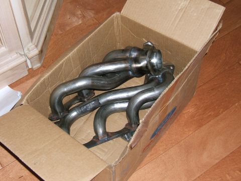 1991 Ford Bronco - A pair of new exhaust headers sit inside a cardboard box, ready for installation.