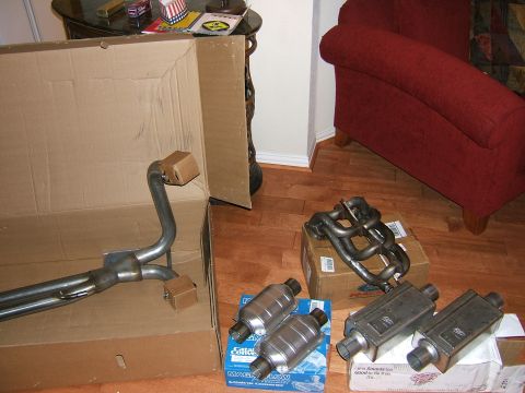1991 Ford Bronco - Several new exhaust system components are laid out on the floor, ready for installation.