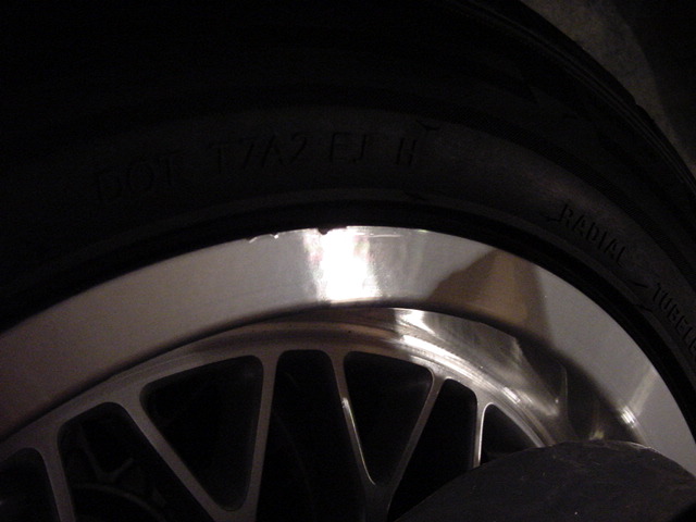 Close-up of a car wheel and tire with some text visible on the tire sidewall