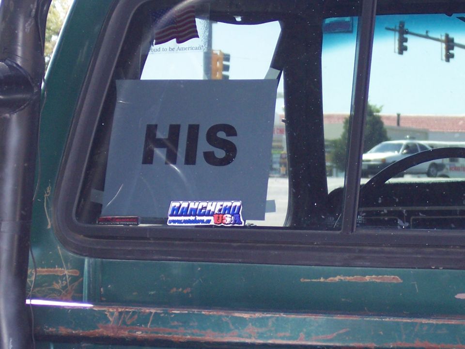 Green vehicle window with 'HIS' sign and Ranchero USA sticker, rusty lower body