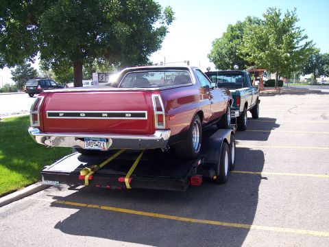 1972 Ford Ranchero - Red 1972 Ford Ranchero being transported on a trailer, with a green pickup truck following.