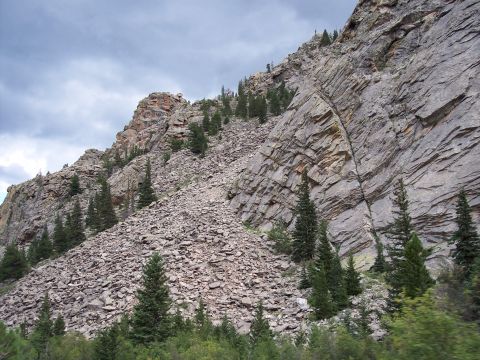 1972 Ford Ranchero - A vast mountain scene with layered rock formations and scattered evergreen trees under a dramatic sky.