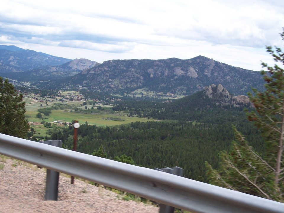 Mountain valley view from a road with guardrail in foreground