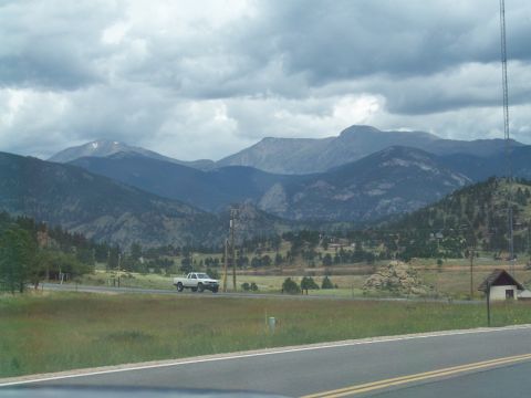1972 Ford Ranchero - A white pickup truck travels along a road with a vast mountain landscape under a cloudy sky.
