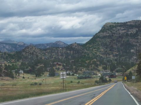 1972 Ford Ranchero - A vehicle drives on a highway through a scenic mountain valley dotted with houses and dense pine trees.