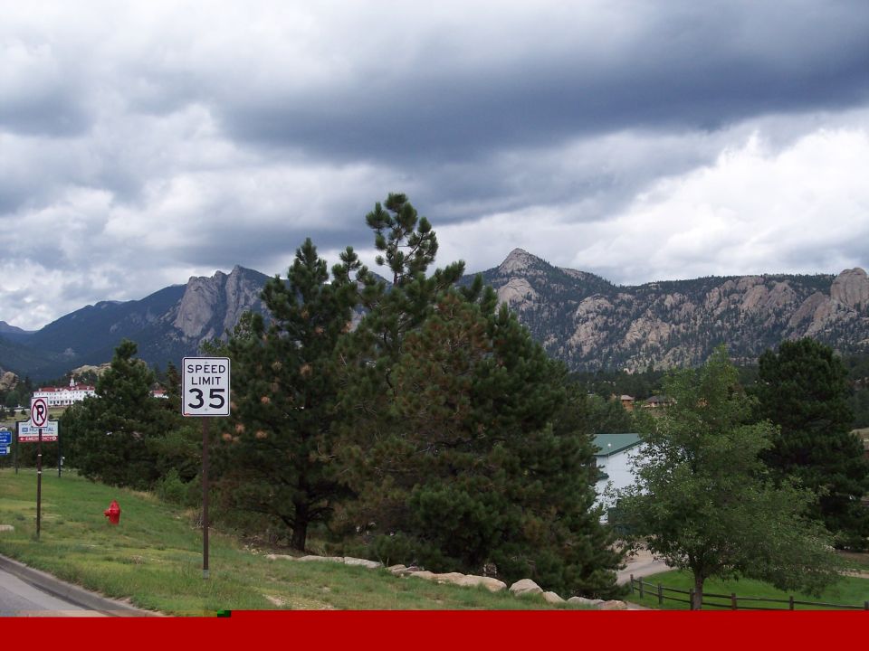 Cloudy mountain scene with pines, a 35 mph sign, and a lake