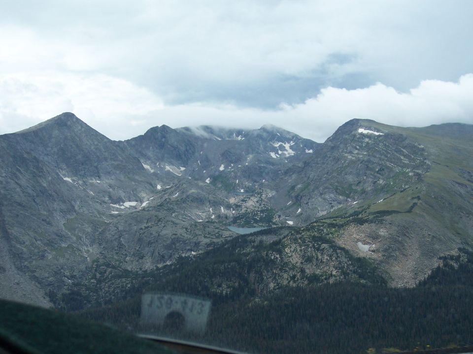Cloudy mountain range with snow patches viewed through a windshield