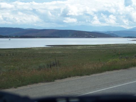 1972 Ford Ranchero - A wide view of a lake and hills under a cloudy sky, taken from a moving vehicle.