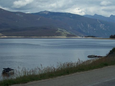 1972 Ford Ranchero - A vast lake is surrounded by mountains under a cloudy sky, with a road in the foreground.