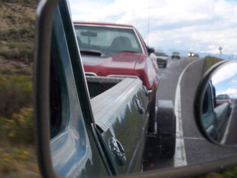 1972 Ford Ranchero - A red pickup truck is viewed from the side, reflecting in a side mirror on a cloudy day.