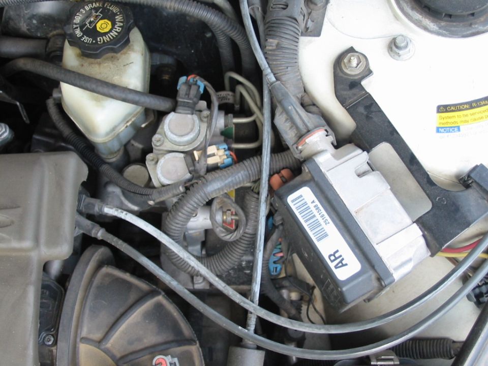 Engine bay close-up showing brake master cylinder, ABS module with barcode, and wiring harnesses