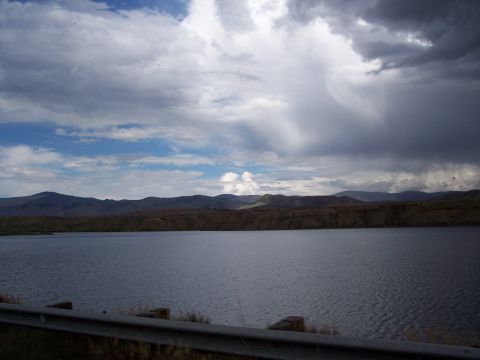 1972 Ford Ranchero - A vast lake stretches towards distant mountains under a sky filled with dramatic, dark clouds.