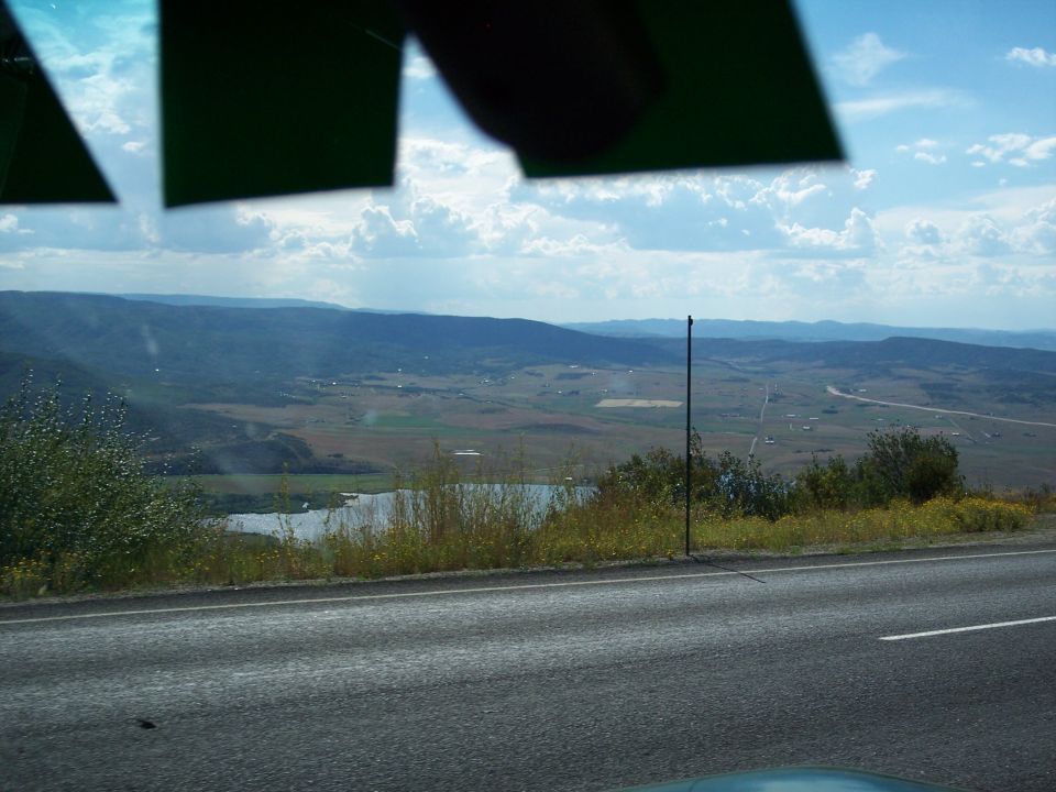 View through windshield of highway and valley landscape under cloudy sky