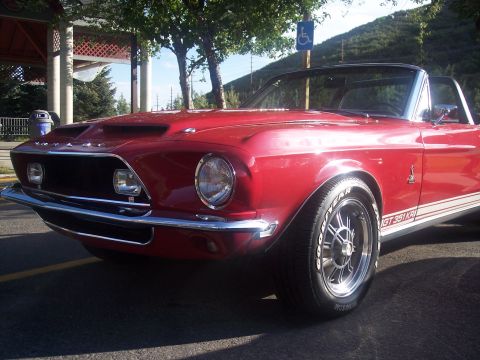 1972 Ford Ranchero - A classic red convertible with prominent hood scoops and side stripes is parked outdoors.