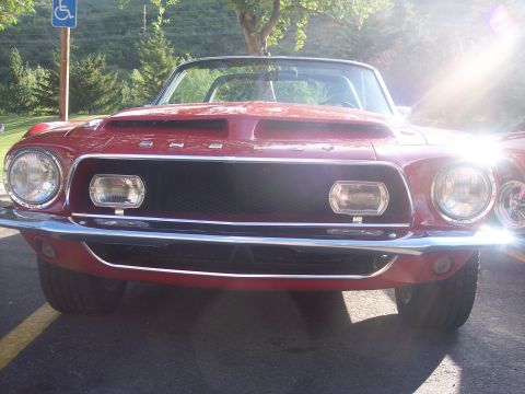 1972 Ford Ranchero - Front view of a red 1969 Ford Mustang convertible with distinctive hood scoops and a chrome bumper.
