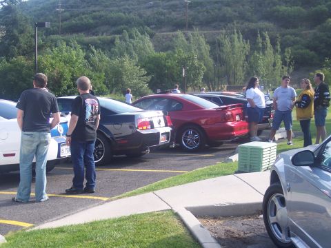 1972 Ford Ranchero - Several Ford Mustangs are parked in a lot, with people standing around them.