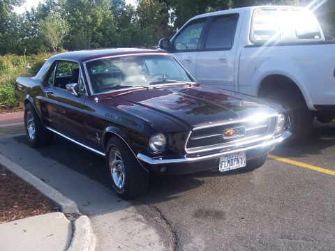 1972 Ford Ranchero - A dark red 1967 Ford Mustang coupe is parked next to a white pickup truck.