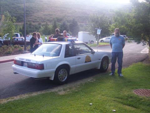 1972 Ford Ranchero - A white 1987 Ford Mustang SSP police car is parked on grass with a man standing next to it.