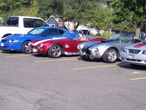 1972 Ford Ranchero - A lineup of vehicles including a pickup, a Mustang, and two AC Cobra replicas parked in a lot.