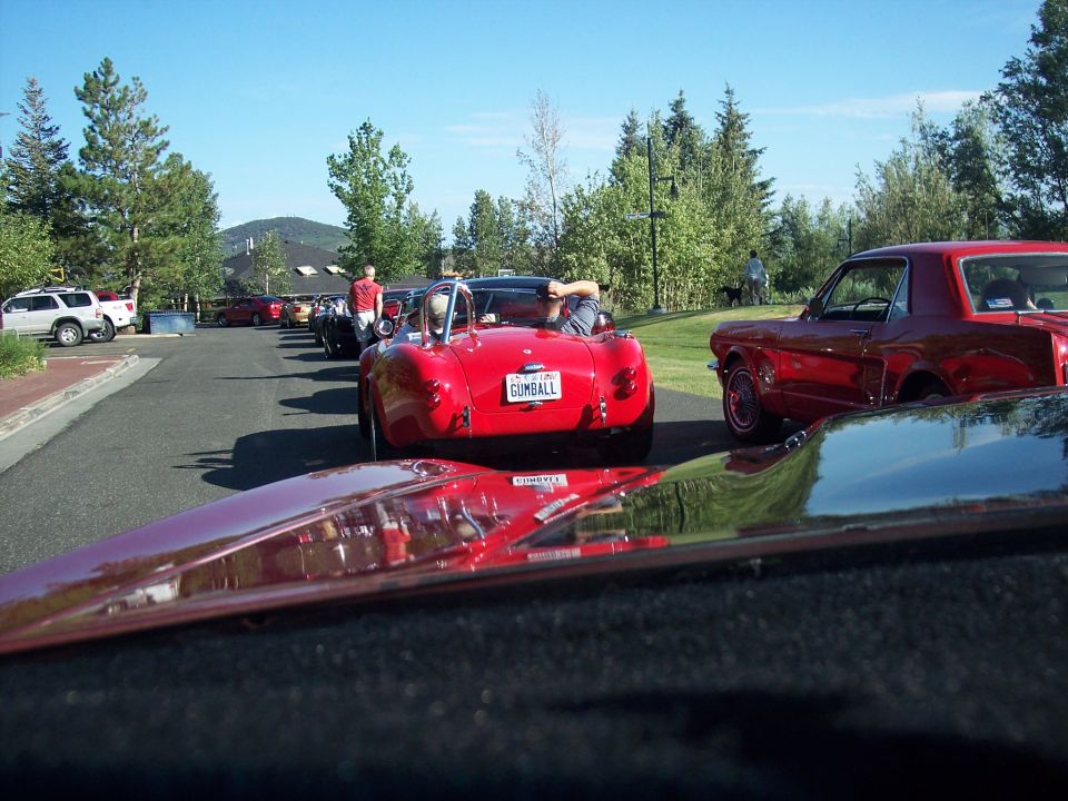 Red Cobra roadster with GUMBALL plate in a car lineup, red Mustang at right