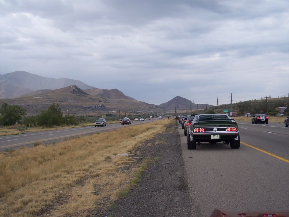 Rear of a dark green muscle car with BOSS plate on a desert highway shoulder