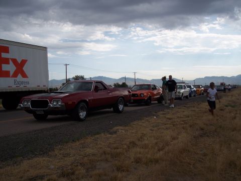 1972 Ford Ranchero - A line of vehicles, including a 1972 Ford Ranchero, are parked or driving along a highway.