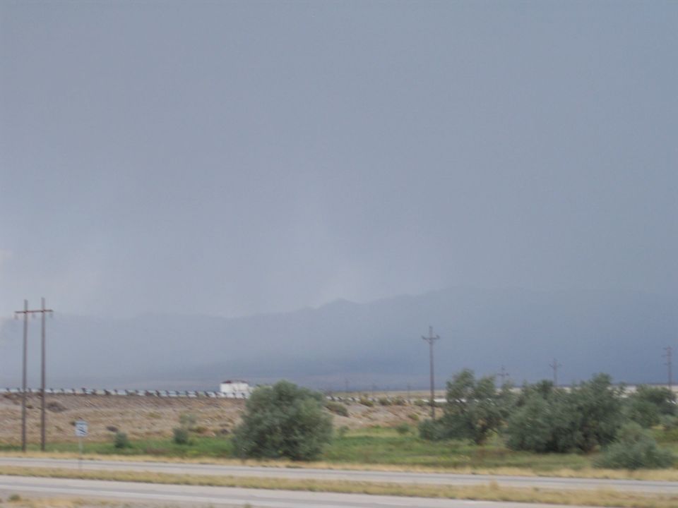 Distant white truck on a road in a hazy desert landscape with power poles and mountains