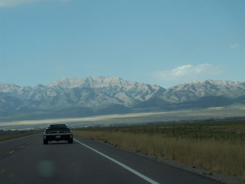 1972 Ford Ranchero - A black coupe travels down an open highway towards a mountain range under a clear blue sky.