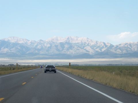 1972 Ford Ranchero - A black 1972 Ford Ranchero cruises down a highway, with a mountain range dominating the horizon.