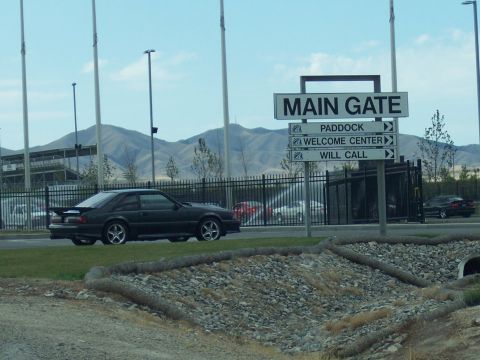 1972 Ford Ranchero - A dark colored hatchback is parked near a sign indicating directions to the main gate and other areas.