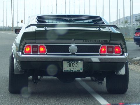 1972 Ford Ranchero - A green 1973 Ford Mustang Mach 1 is seen from the rear, displaying its "BOSS" license plate and distinctive louvers.