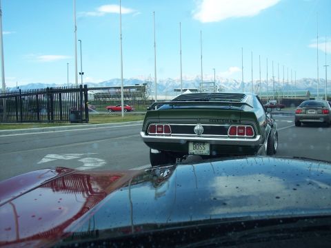 1972 Ford Ranchero - Green 1971 Ford Mustang Mach 1 with a BOSS license plate, driving on a road with mountains in the background.