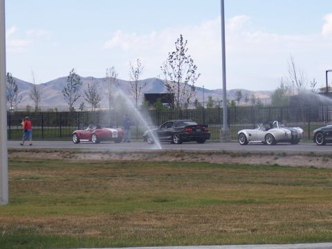 1972 Ford Ranchero - A line of sports cars is visible on the road, with water being sprayed on one of the vehicles.