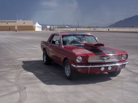1972 Ford Ranchero - A classic red Ford Mustang sits in an empty lot under a cloudy sky.
