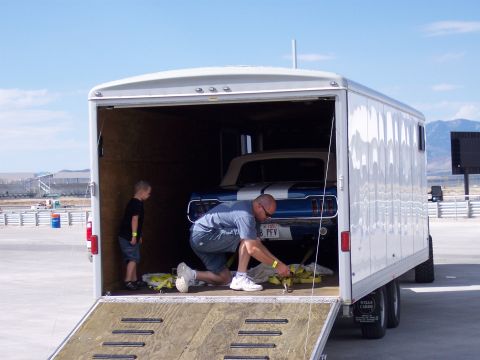 1972 Ford Ranchero - A man secures a blue 1966 Ford Mustang convertible with white racing stripes inside a trailer.
