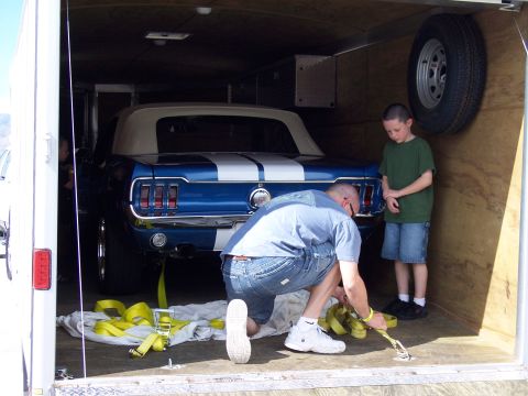 1972 Ford Ranchero - A blue convertible with white racing stripes is being secured in a trailer with yellow straps.