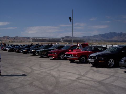 1972 Ford Ranchero - A line of Ford Mustangs, including a red 1970 model, are parked on a track under a bright blue sky.